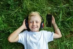 Kind; Musik; Kopfhörer; Kopfhoerer; hören; hoeren; Gras; Sommer; Freizeit; Hörbuch; Hoerbuch; entspannen; audio; Sommerferien; lachen; Spaß; Spass;