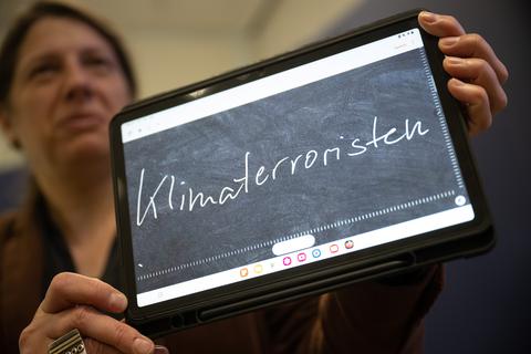 Constanze Spieß, Professorin am Institut für Germanistische Sprachwissenschaft der Philipps-Universität Marburg, hält ein Tablet in der Hand, auf dem das "Unwort des Jahres" 2022, "Klimaterroristen", geschrieben steht. 
