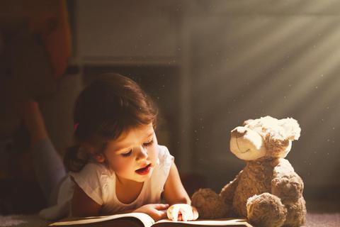 Vorlesen ist der erste Schritt – hier hört auch der Teddy aufmerksam zu. Foto: AdobeStock – JenkoAtaman