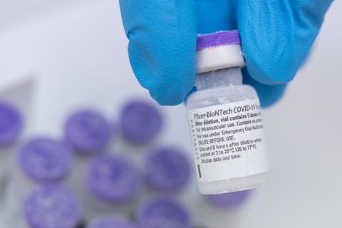 Ein Arzt hält eine Ampulle des Corona-Impfstoffs von Biontech und Pfizer zwischen den Fingern.  Foto: dpa