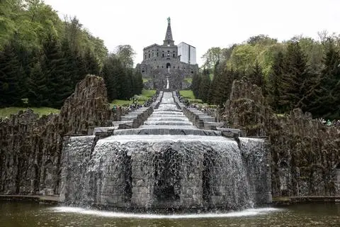 Besucher stehen bei den Wasserspielen im UNESCO-Welterbe Bergpark Wilhelmshöhe an den Kaskaden unterhalb des Herkules-Denkmals. (zu dpa: «Lust auf Kultur? Diese Welterbe-Stätten liegen in Hessen») +++ dpa-Bildfunk +++