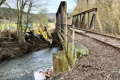Ein Schreitbagger räumt das Bachbett unter der Windesheimer Eisenbahnbrücke. Die Auskolkungen unter den Pfeilern müssen gestopft, zahlreiche Metallteile einschließlich der Schienen erneuert werden.