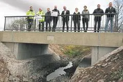 Florian Schmidt, Marco Römer, Niclas Heger, Julien Neubert (mit Förderbescheid), Stefan Jung-Diefenbach, Jennifer Herschbach, Leonie Roßberger, Ralf Ufer und Jens Janik (v.l.) bei der offiziellen Einweihung der neuen Brücke über den Weidgraben vor dem Rückhaltebecken in Lich.