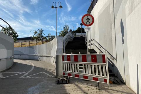 Verbotsschild und Warnbake sichern den westlichen Treppenaufgang hinter der Bahnunterführung. Die Bauarbeiten verzögern sich. Foto: Detlef Volk