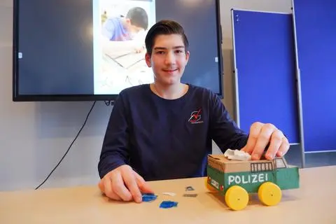 Simon Krieger mit seinem sparsamen Polizeibus. Mit fünf Tropfen Salzwasser ist das Gefährt 15 Minuten mobil. Im Hintergrund läuft das Video, mit dem der 13-Jährige die Jury überzeugt hat.