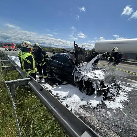 Mit Schaum löscht die Feuerwehr den brennenden Motor des Autos auf der A3.