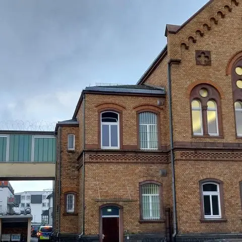 Der Prozess um den Mord an einer zur vermuteten Tatzeit 25-jährigen Frohnhäuserin findet im ersten Stock des Landgerichts Limburg in Saal 129 (rechts) statt. Während die beiden per Gefangenentransport nach Limburg gefahrenen, mit Handschallen gefesselten Angeklagten im Erdgeschoss aus den Fahrzeugen aussteigen, ist der vermutliche Haupttäter in der JVA Limburg untergebracht, die über einen Übergang im ersten Stock mit dem Gerichtsgebäude verbunden ist.