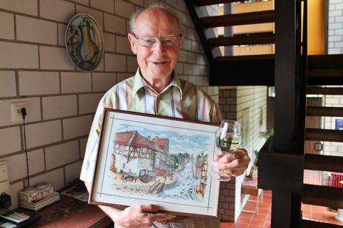 Mit einem Glas Wickerer Wein und einer historischen Ansicht der Frankfurter Straße bringt der ehemalige Erste Stadtrat Norbert Hegmann seine Verbundenheit mit beiden Stadtteilen zum Ausdruck. Alexander Noé
