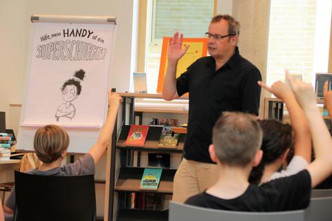 Der Autor Rüdiger Bertram gewann 2022 das Projekt „Kinder-Jury“ der Hofheimer Stadtbücherei. Jetzt hat er aus seinem Buch „Hilfe, mein Handy ist ein Superschurke!“ vorgelesen. Ralph Keim