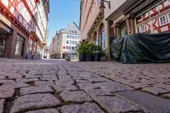 Tische und Stühle stehen eingepackt im Frühjahr 2020 vor den Kneipen in Marburg. Trotz strahlenden Sonnenscheins ist die Flaniermeile in der Oberstadt menschenleer.