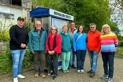 Der Biskirchener Ortsbeirat und die Paten präsentieren den neuen Bücherschrank auf dem Dorfplatz.
