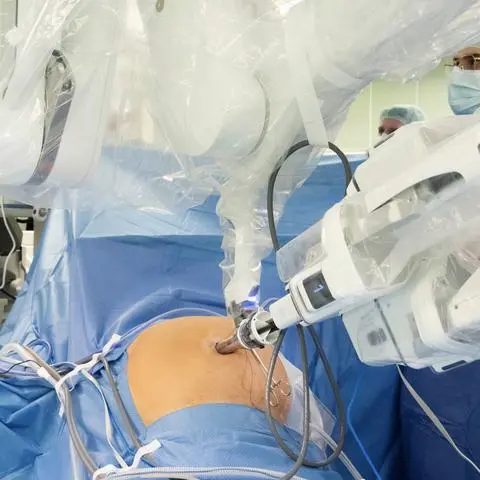 Im Vordergrund der Patient, im Hintergrund Professor Peter Grimminger, der am Bildschirm den Roboter-Arm und seine zahlreichen Instrumente steuert.