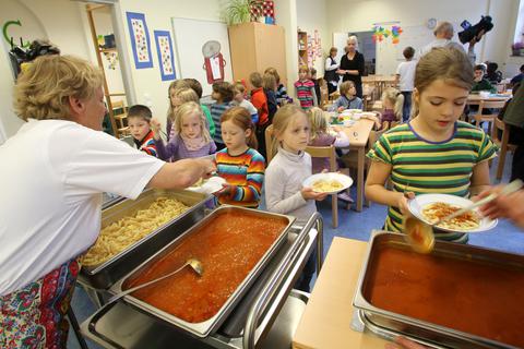 Schüler einer offenen Ganztagsschule bekommen ihr Mittagessen auf die Teller portioniert.  Foto: dpa
