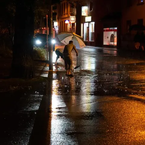 Ein schweres Unwetter hat am Mittwochabend die Region getroffen: Hier versuchen zum Beispiel Menschen in Mörfelden-Walldorf, das Wasser in einen Gulli zu kehren.