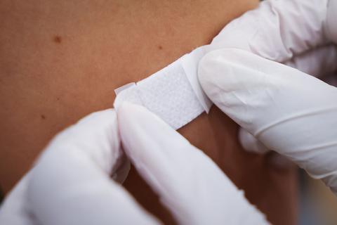 Eine Ärztin klebt einer Person nach der Impfung ein Pflaster auf den Arm.