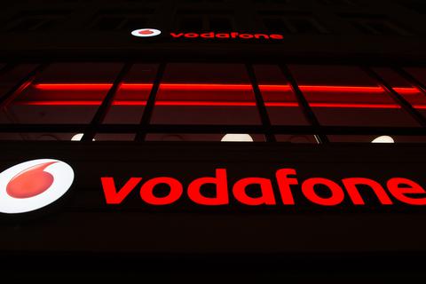 Das Vodafone-Logo leuchtet an einem Laden des Mobilfunkanbieters. Foto: dpa