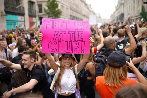 Eine Frau hält ein Schild mit dem Schriftzug "Meet me at the club" (Triff mich im Klub) hoch. Foto: dpa