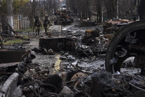 Zwei ukrainische Soldaten gehen auf einer Straße, die übersät ist mit zerstörten russischen Militärfahrzeugen. In der ukrainischen Stadt Butscha, 25 Kilometer nordwestlich der Hauptstadt Kiew, bietet sich nach dem Rückzug der russischen Armee ein Bild des Grauens.  Foto: Rodrigo Abd/AP/dpa