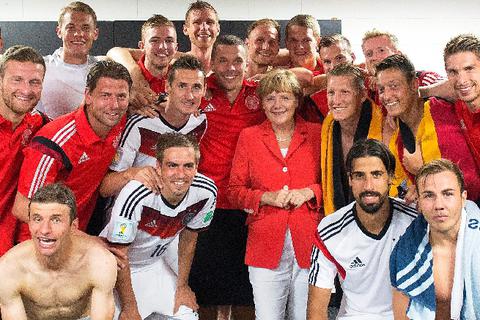 WM-Pokal als vorgezogenes Geburtstagsgeschenk zum 60.: Die Weltmeistermannschaft 2014 und Kanzlerin Angela Merkel. Foto: dpa