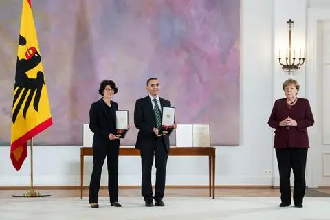 Die Biontech-Gründer Özlem Türeci (links) und Ugur Sahin (Mitte) stehen bei der Verleihung des Großen Verdienstkreuzes mit Stern des Verdienstordens der Bundesrepublik Deutschland im Schloss Bellevue mit Bundeskanzlerin Angela Merkel (rechts) zusammen.  Foto: dpa