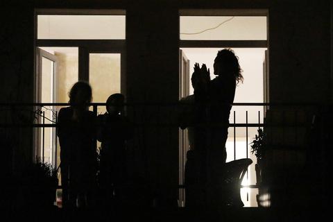 An einem Fenster applaudieren Menschen nach einem Balkonkonzert. Foto: dpa
