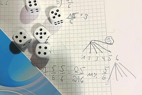 Auf einem Matheheft mit Notizen zur Wahrscheinlichkeitsrechnung liegen fünf Würfel - Mathe in der Praxis.