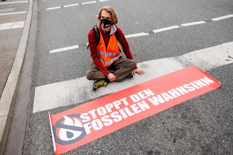 Ein Aktivist der Gruppe "Letzte Generation" mit am Boden angeklebter Hand bei einer Protestaktion in München.
