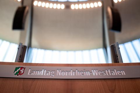 Auf dem Podium des Sitzungssaals in Düsseldorf steht "Landtag Nordrhein-Westfalen". Foto: dpa