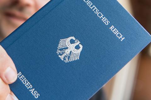 Ein Mann hält ein Heft mit dem Aufdruck „Deutsches Reich Reisepass“ in der Hand. Sogenannte Reichsbürger leugnen die Existenz der Bundesrepublik Deutschland.
