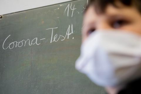 Ein Schüler vor einer Schultafel mit der Aufschrift "Corona-Test". Foto: dpa