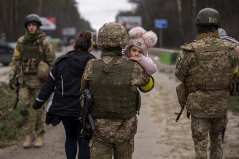 Ein ukrainischer Soldat trägt ein Baby und hilft einer fliehenden Familie bei der Überquerung des Flusses Irpin in den Außenbezirken von Kiew, Ukraine.  Foto: dpa