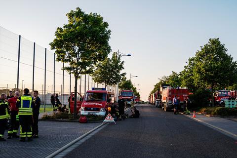 Waldbrand in der Pfalz: Feuerwehrfahrzeug sind an einem Sportplatz in der Nähe des Waldbrands geparkt.