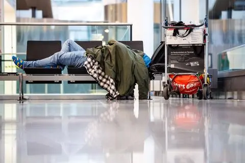 Mann schläft am Münchner Flughafen auf einer Sitzbank