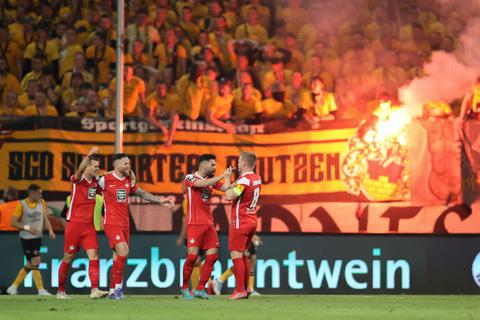 Die Spieler von Kaiserslautern jubeln nach dem Treffer zum 0:1 durch Daniel Hanslik (rechts). Im Hintergrund zünden Fans von Dresden bengalische Feuer.  Foto: dpa
