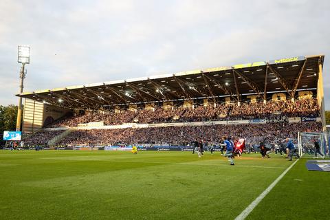 Gleich ist er mittendrin – doch eigentlich will er nur noch weg: Marcel Schuhen (in Gelb) Sekunden nach dem feststehenden Aufstieg. Hinter ihm nähern sich bereits die ersten Fans, die den Platz stürmen.