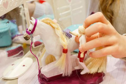 Ein Mädchen spielt mit einem Beauty-Salon für Spielzeugpferde von Schleich.