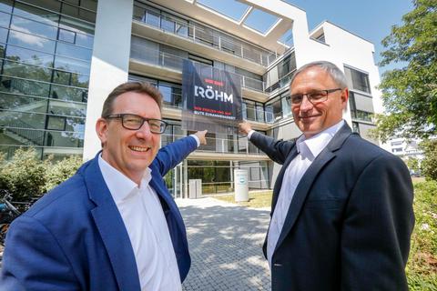 Ronald Ayles von Advent (links), Röhm-Geschäftsführer Michael Pack und das neue Firmenlogo am Verwaltungssitz. Foto: Torsten Boor 